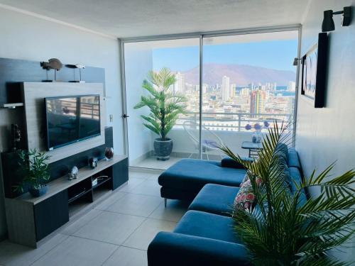 a living room with a blue couch and a large window at Departamento con espectacular Ubicación, Vista al Mar y Panorámica a todo Iquique in Iquique