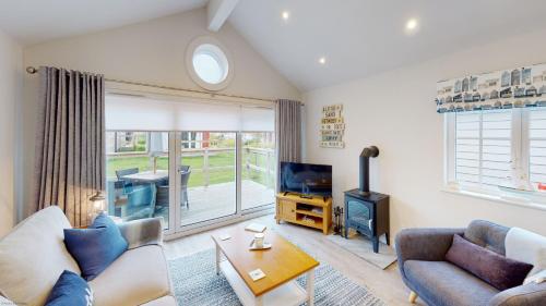 a living room with a couch and a tv at Bay Breeze - Part of the The Bay Filey Holiday Village with pool, gym and direct beach access, pub, restaurant, tennis and meadows walks in Filey