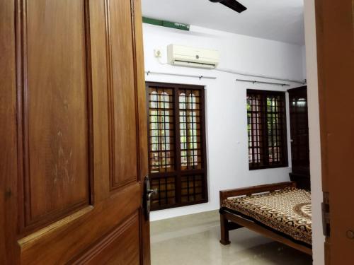 a room with a door and a bench and windows at Kizhakkethottam Homestays-River View Villa in Pala