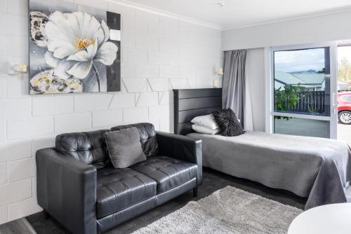 1 dormitorio con sofá, cama y ventana en Dunrovin Motel en Taupo