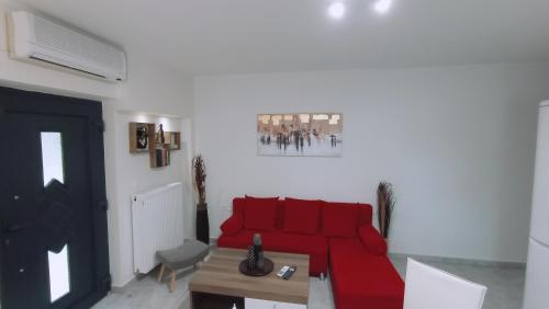 a living room with a red couch and a table at Angela's Seaside Luxury Flat in Lefkandi Chalkidas