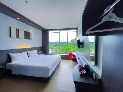 a bedroom with a white bed and a large window at Neo Dipatiukur Bandung by ASTON in Bandung