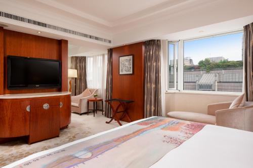 a hotel room with a bed and a flat screen tv at Hangzhou Xinqiao Hotel in Hangzhou