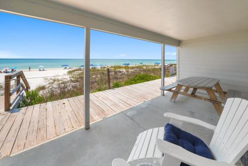 a porch with chairs and a picnic table and the beach at Three Steps to the Beach Townhouse in Inlet Beach
