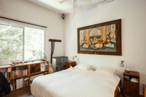 a bedroom with a bed and a painting on the wall at Frishman beach 2Br full of art and light in Tel Aviv