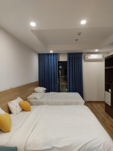 two beds in a bedroom with blue drapes at TMS Beachfront Quy Nhon - Holiday Apartment in Quy Nhon