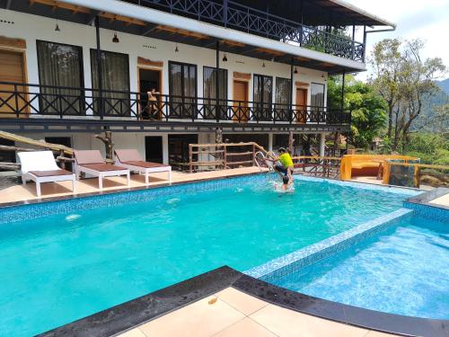 a person playing in the water in a swimming pool at The Wild Trails Munnar Resort in Munnar