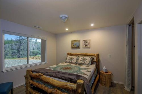 a bedroom with a bed and a large window at Cozy Cub Cabin, brand new home near Yosemite in Mariposa