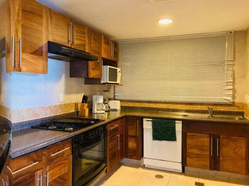 a kitchen with wooden cabinets and a stove top oven at Condominio en Ixtapa frente a la playa in Ixtapa