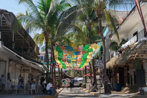 a street with palm trees and people walking down a street at Sayulita Central Hotel in Sayulita