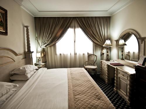 a bedroom with a large bed and a vanity and a window at Ramada By Wyndham Fes in Fès