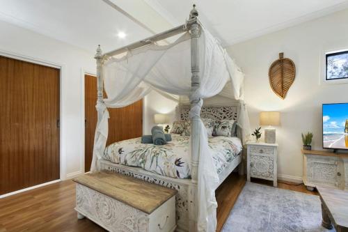 a bedroom with a white canopy bed with a wooden floor at Bluelake Cottage Metung in Metung