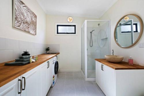 a white bathroom with a sink and a mirror at Bluelake Cottage Metung in Metung