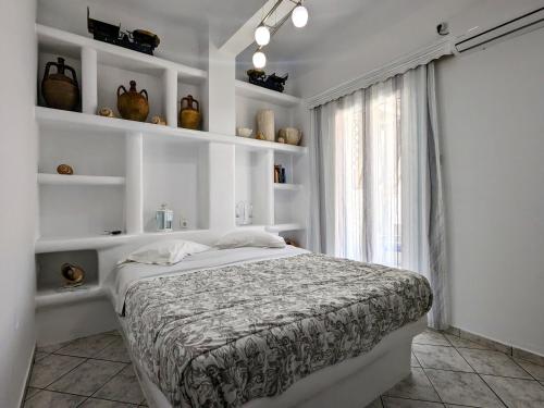 1 dormitorio con 1 cama con paredes y estanterías blancas en Anoi Rooms en Tinos Town