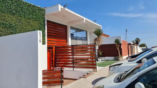 una casa con una valla de madera junto a un aparcamiento en Suites & Habitaciones Acapulco La Lisera, en Arica