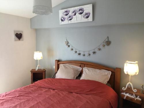- une chambre avec un lit avec un couvre-lit rouge et deux lampes dans l'établissement Belle longere 130 m2 aux portes du marais poitevin, à Niort