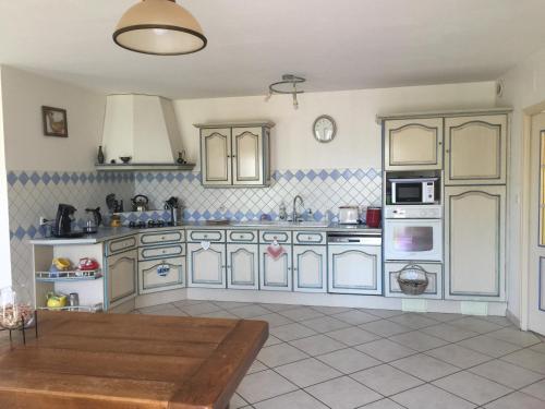 une cuisine avec des placards bleus et blancs et une table dans l'établissement Belle longere 130 m2 aux portes du marais poitevin, à Niort