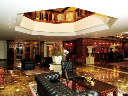 a lobby with a couch and a table and chairs at Ramada By Wyndham Fes in Fès