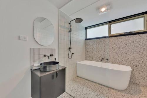a bathroom with a tub and a sink and a mirror at Parnella Hideaway in St Helens