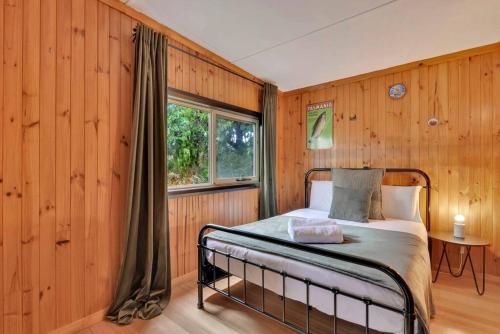 Schlafzimmer mit Holzwänden und einem Bett mit Fenster in der Unterkunft Parnella Hideaway in St Helens