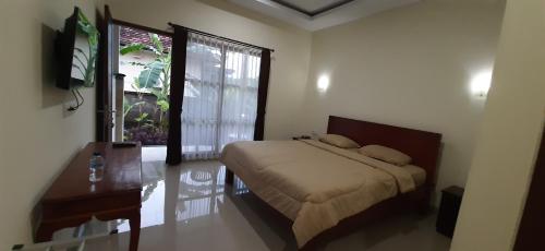 a bedroom with a bed and a desk and a window at Kubu doble in Sanur