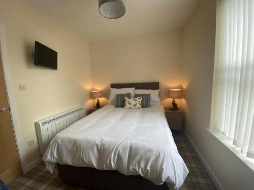 een slaapkamer met een groot wit bed met 2 lampen bij The Burrow, Langholm, Dumfries and Galloway in Langholm