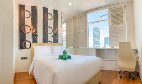 um quarto com uma cama branca e uma janela em Soho Suites KLCC by Alucard's Cat em Kuala Lumpur