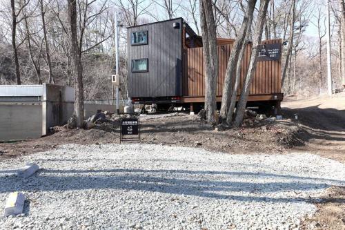 a tiny house sitting on top of some trees at サウナバーベキュージャグジー完全貸し切りという贅沢大人の秘密基地#01 in Miyota