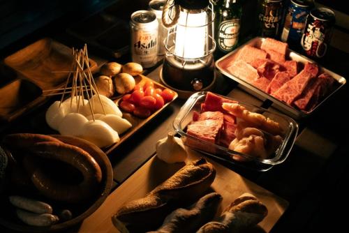 a table topped with trays of different types of food at サウナバーベキュージャグジー完全貸し切りという贅沢大人の秘密基地#01 in Miyota