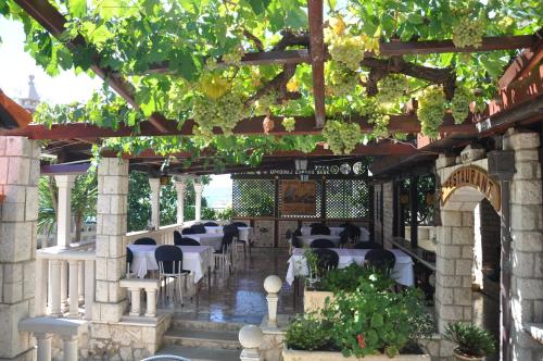 a restaurant with white tables and chairs and vines at Villa Segetski dvori - Tradition since 1964 in Trogir