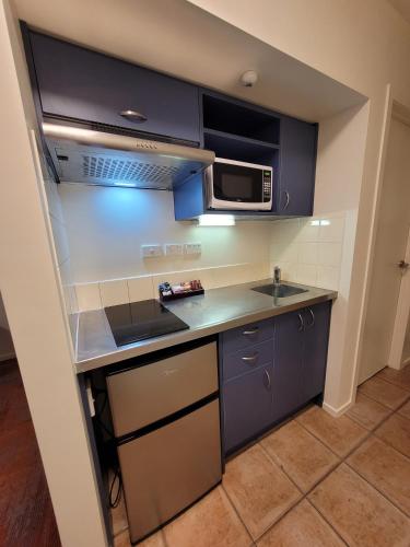a small kitchen with a sink and a microwave at City of Sails Motel in Auckland