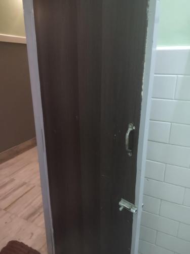 a black door in a bathroom with a wall at Krishna Lodge in Tiruchchirāppalli