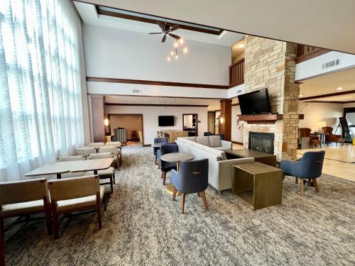 Staybridge Suites Milwaukee West-Oconomowoc, an IHG Hotel في اوكونوموووك: لوبي الفندق مع طاولات وكراسي ومدفأة