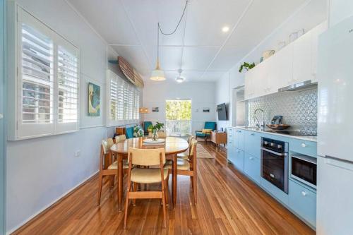 a kitchen with a dining table and blue cabinets at Stylish 1950s Moffat Beach House in Caloundra