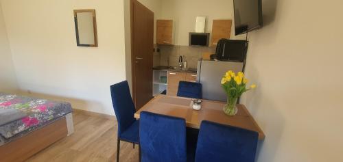 a dining room table with blue chairs and a vase of flowers at Zajazd Stronie in Stronie Śląskie