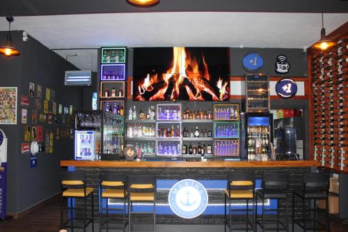 a bar with a fireplace behind the bar with stools at Burhaniye Marina Boutique Hotel in Burhaniye