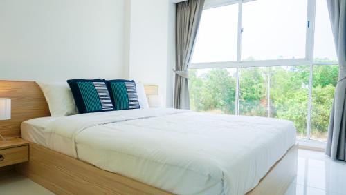 a bed in a bedroom with a large window at Mirage Condominium in Sattahip