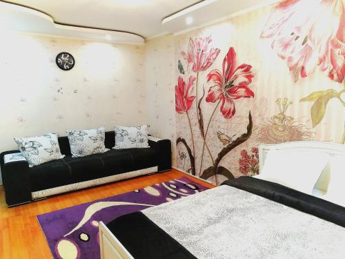 a bedroom with a black couch and a flower wallpaper at 429. Отличный вариант для туриста и командированного in Almaty