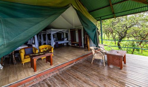 een tent met een tafel en stoelen op een houten terras bij Ngorongoro Wild Camp in Ngorongoro