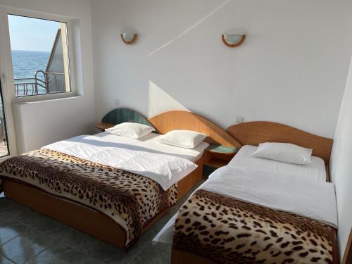 two beds in a room with a view of the ocean at Vila Jolie in Costinesti