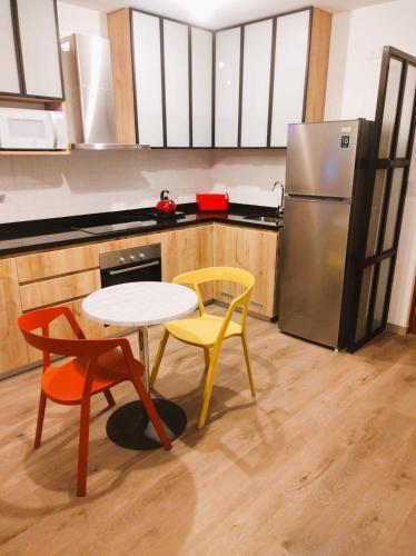 a kitchen with two chairs and a table and a refrigerator at LA POSADA DE GUILLE LUXURY 1 HABITACION - Surco in Lima
