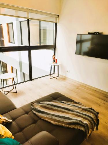a living room with a couch and a flat screen tv at LA POSADA DE GUILLE LUXURY 1 HABITACION - Surco in Lima