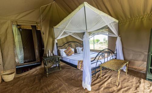 ein Schlafzimmer mit einem Himmelbett in einem Zelt in der Unterkunft Serengeti Wild Camp in Serengeti-Savanne