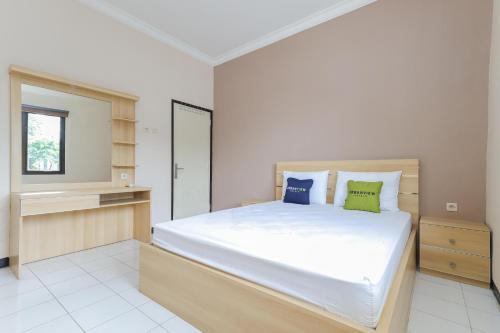 a bedroom with a large white bed and a window at Urbanview Roemah Tebet by RedDoorz in Jakarta