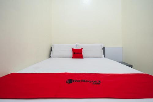 a red and white bed with a red pillow on it at RedDoorz Syariah near RS Tentara Solok in Solok
