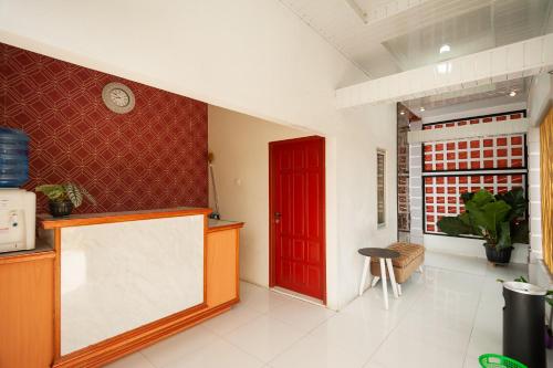 a kitchen with a red door and a white floor at RedDoorz Syariah near RS Tentara Solok in Solok