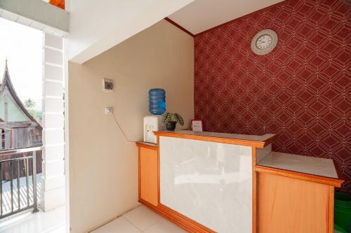 a room with a counter and a clock on a wall at RedDoorz Syariah near RS Tentara Solok in Solok