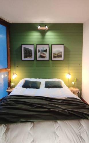 a bedroom with a large bed with a green wall at Appartement cosy cœur de station in Villard-de-Lans