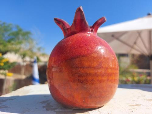 a red pomegranate statue sitting on a table at הצימר של כרמית in Neve Zohar
