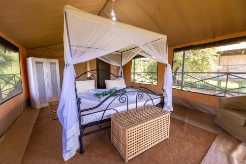 a bedroom with a canopy bed in a tent at Ikoma Wild Camp in Robanda
